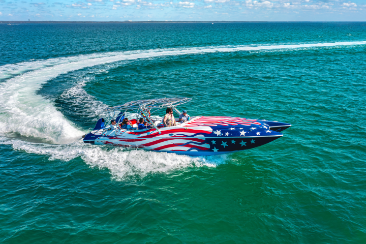 Speedboat with American flag design making a sharp turn on the ocean.
